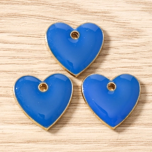 Close-up of three blue enamel heart charms with gold metal edges for DIY jewelry making