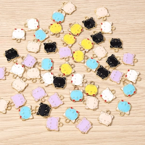 Nahaufnahme bunter Emaille-Katzenanhänger für DIY-Schmuck auf hellem Holzgrund