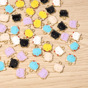 Makro-Detail von bunten Emaille-Katzenkopf-Anhängern mit Goldmetallkante für DIY-Schmuck