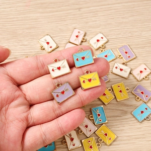 Gros plan de breloques enveloppes émaillées colorées pour la création de bijoux DIY