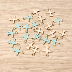 Detalle de dijes esmaltados con forma de avión para la creación de joyería artesanal