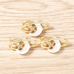 Détail macro de trois breloques dorées lune et étoile pour création de bijoux sur bois