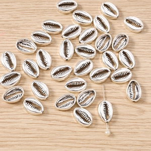Dettaglio macro di ciondoli a conchiglia d'argento con texture realistica e foro praticato