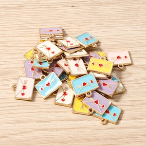 Vue macro de breloques enveloppes émaillées colorées avec cœur rouge sur bois clair