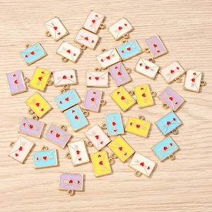 Gros plan de breloques enveloppes en émail coloré avec motifs de cœur pour bijoux DIY