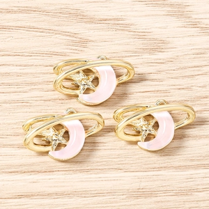 Détails de trois pendentifs lune en émail rose et étoile dorée sur surface en bois