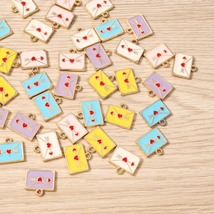 Vue détaillée de breloques enveloppes émaillées colorées avec motifs cœur pour bijoux DIY