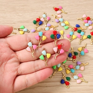 Detail of colorful enamel balloon charms for DIY jewelry making held in hand over a desk