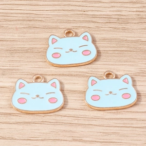 Détail de trois breloques chat en émail bleu clair avec finition dorée pour bijoux