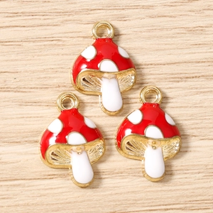 Detalle de dijes de hongo rojos con lunares blancos y acabado de metal dorado fino