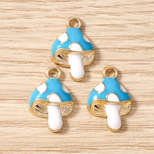 Detalle macro de dijes de hongos azules con lunares y aros dorados para joyería DIY
