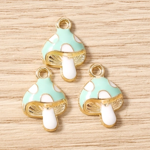 Detalle de dijes de hongo verde menta con puntos blancos y lazos dorados para joyería DIY
