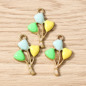 Close-up of enamel heart balloon charms in blue green and yellow for jewelry making