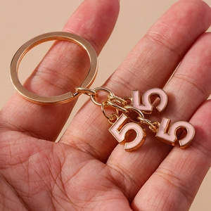 Close-up of pink enamel number 5 charms on a gold polished keychain ring pendant