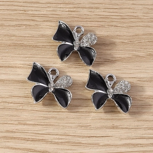 Silver butterfly pendants with black enamel and white rhinestones on wood surface