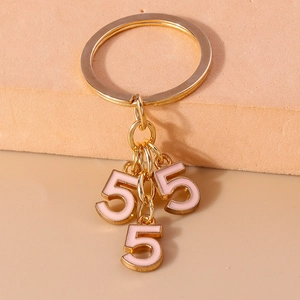 Close-up of golden keychain featuring three pink enamel number five charms on a display stand
