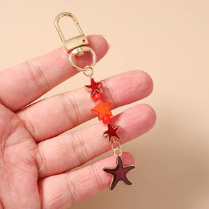 Close-up of golden star-shaped keychain with red glitter and orange bead charms