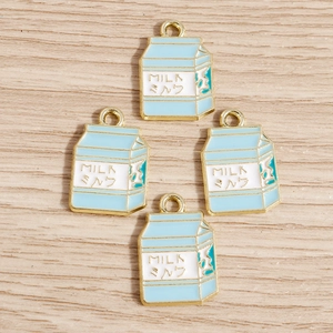 Vista macro di quattro ciondoli a forma di cartone del latte smaltati blu e bianchi per fai da te