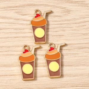 Détail de pendentifs émaillés en forme de thé au lait pour bijoux DIY sur fond bois