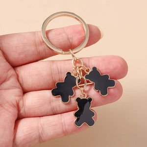 Detalle de llavero dorado con tres colgantes de oso en esmalte negro brillante