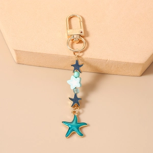Detailed close-up of blue and white starfish charms on golden enamel lobster clasp keychain
