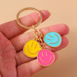 Smiling face keychain with colorful enamel pendants in yellow, blue and pink with gold ring