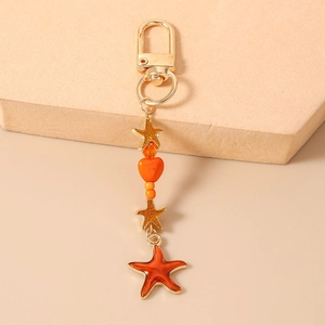 Detail of orange starfish keychain with golden star charms and heart beads on display