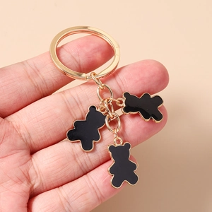 Detalle de un llavero dorado con tres colgantes de osos en esmalte negro sobre anillo grande