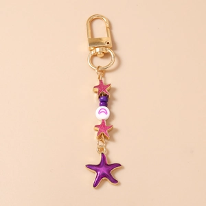 Detail of starfish keychain with purple beads and pink enamel charms on gold clasp