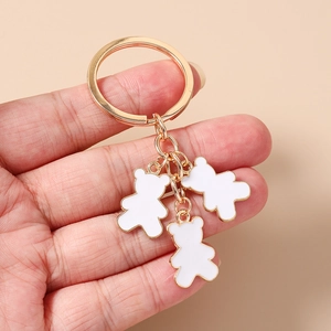 Detalle de los colgantes de oso de esmalte blanco y el anillo de metal dorado en mano