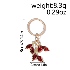 Detailed macro view of golden leaf keychain with dark red enamel finish and measurements