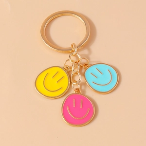 Detail of colorful smiley face pendants in yellow blue and pink on a gold metal keychain