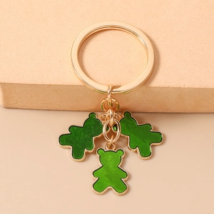 Detalle de un llavero dorado con tres colgantes de ositos verde esmeralda translúcido