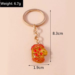 Detail showing a yellow Christmas glove keychain with red waves and golden glitter texture