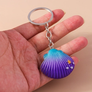 Macro view of a gradient shell keychain with star and bead detail held by hand