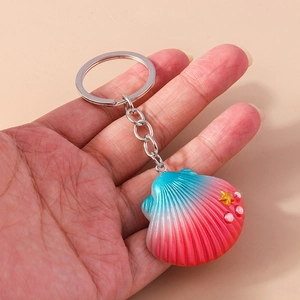 Detail of gradient blue and pink shell keychain with golden starfish and pearl decor