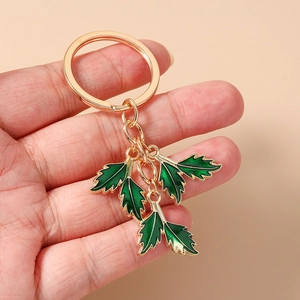 Detailed close-up of golden keychain with four dark green enamel leaf-shaped pendants