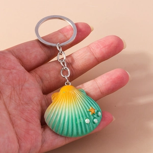 Close-up of a gradient shell keychain with orange starfish details held in hand
