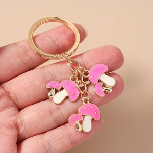 Dettaglio di portachiavi a doppio fungo rosa con anello in metallo dorato in mano