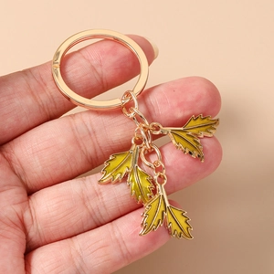 Detail of hand holding gold leaf keychain with yellow enamel inlay and metallic finish