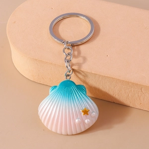 Close-up of ocean shell keychain with gold stars and pearls on warm peach display