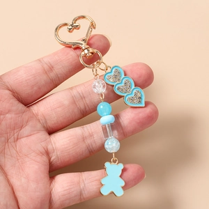 Dettaglio di un portachiavi a cuore blu con catena di perline e ciondolo a orsetto