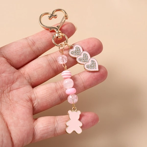 Dettaglio di un portachiavi rosa con perline, ciondoli a cuore e pendente a orsetto