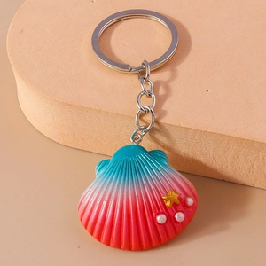 Macro shot of gradient sea shell keychain with golden star and white pearls detail