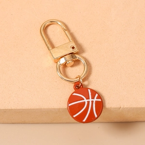 Detailed close-up of a basketball keychain with golden lobster clasp on a beige background
