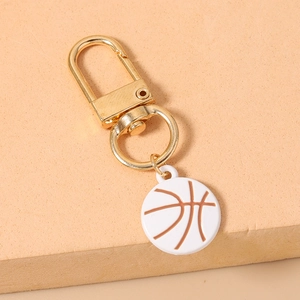 Detailed close-up of a white basketball keychain with gold metal buckle on orange stand