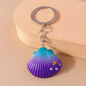 Detailed view of a gradient purple shell keychain with a gold star and white faux pearls