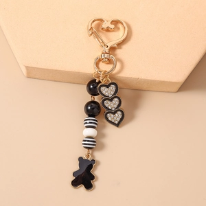 Dettaglio di un portachiavi a cuore dorato con cuori di cristallo e un orsetto nero