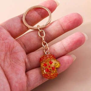 Close-up of a red glittery Christmas glove keychain with golden metal ring and chain