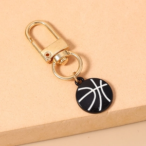 Detail of a polished gold lobster clasp and round black basketball keychain charm